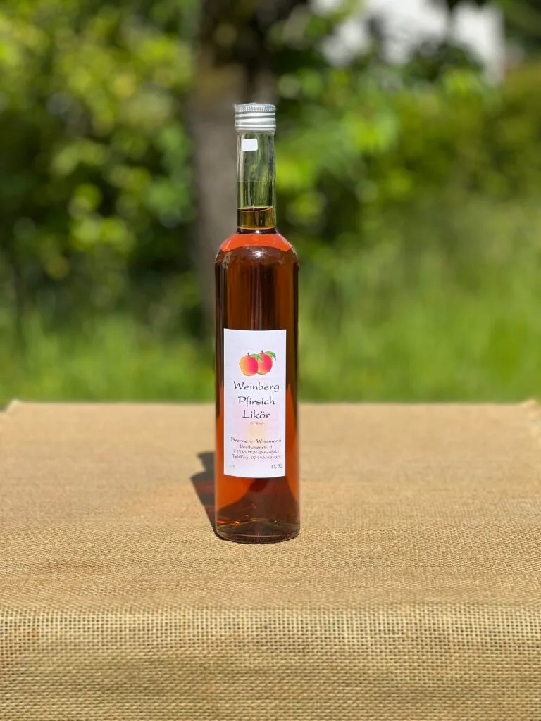 Eine Flasche Pfirsichlikör auf einem Tisch mit idyllischem grünen Hintergrund.