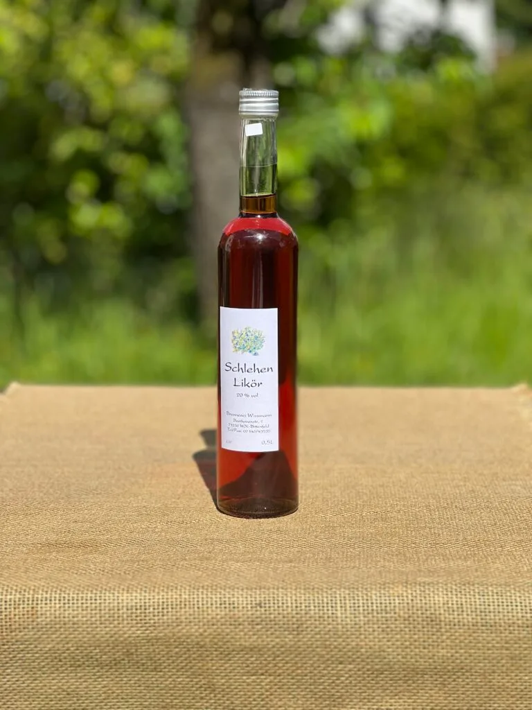 Eine Flasche Schlehen-Likör auf einem Tisch mit idyllischem grünen Hintergrund.