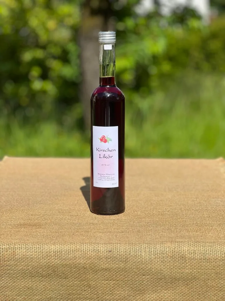 Eine Flasche Kirschen-Likör auf einem Tisch mit idyllischem grünen Hintergrund.