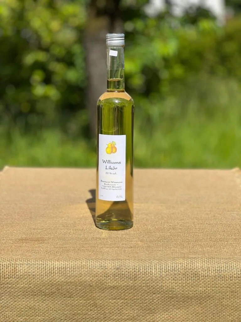 Eine Flasche Williams-Likör auf einem Tisch mit idyllischem grünen Hintergrund.