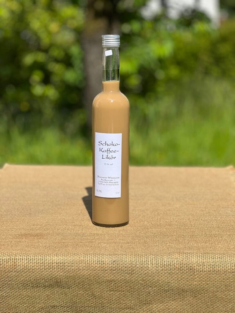 Eine Flasche Schoko-Kaffee-Likör auf einem Tisch mit idyllischem grünen Hintergrund.