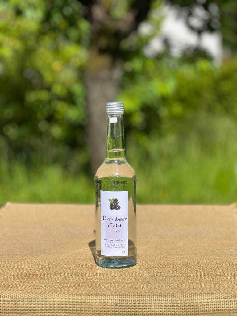 Eine Flasche Brombeergeist auf einem Tisch mit idyllischem gr&uuml;nen Hintergrund.