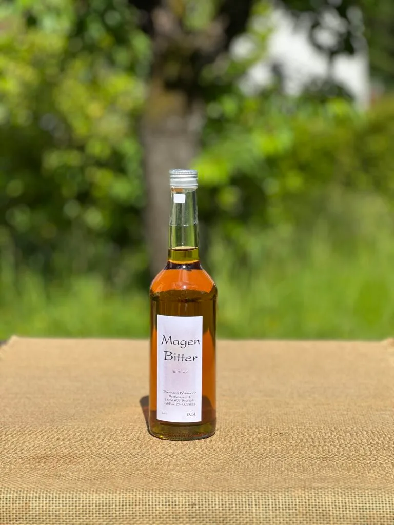 Eine Flasche Magenbitter auf einem Tisch mit idyllischem grünen Hintergrund.