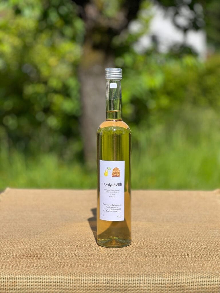 Eine Flasche Honig-Williams auf einem Tisch mit idyllischem grünen Hintergrund.