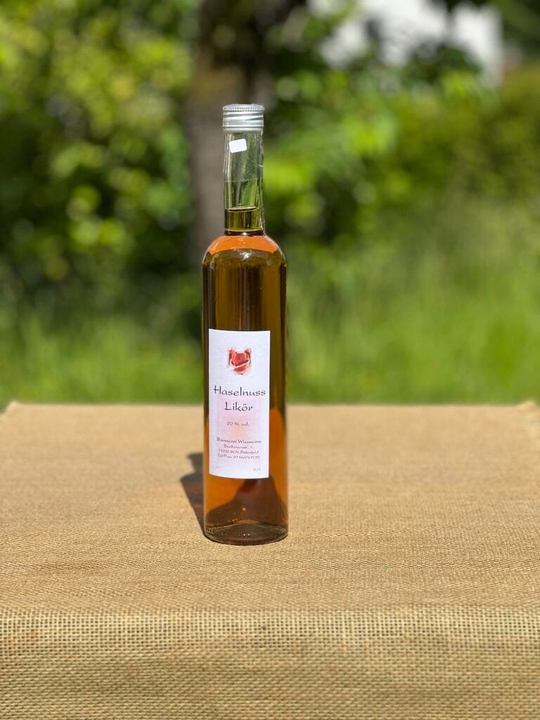 Eine Flasche Haselnuss-Likör auf einem Tisch mit idyllischem grünen Hintergrund.